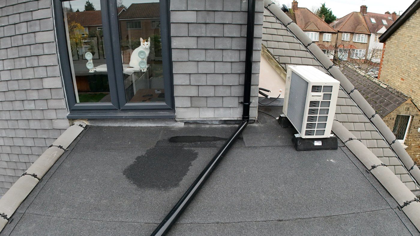 Close-proximity drone view of flat roof deck showing substantial standing water in lower central section