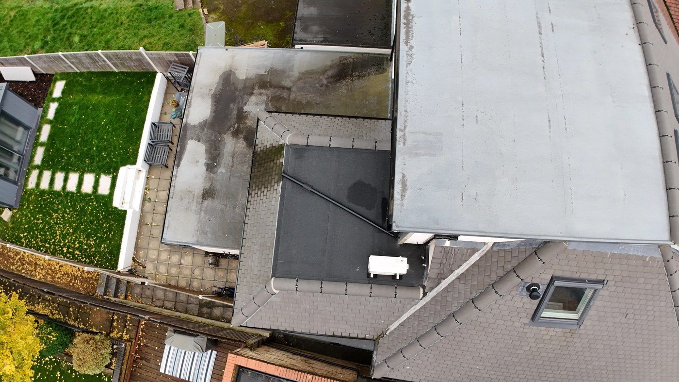 High-altitude nadir shot showing flat roof sections with dark staining confirming persistent water retention