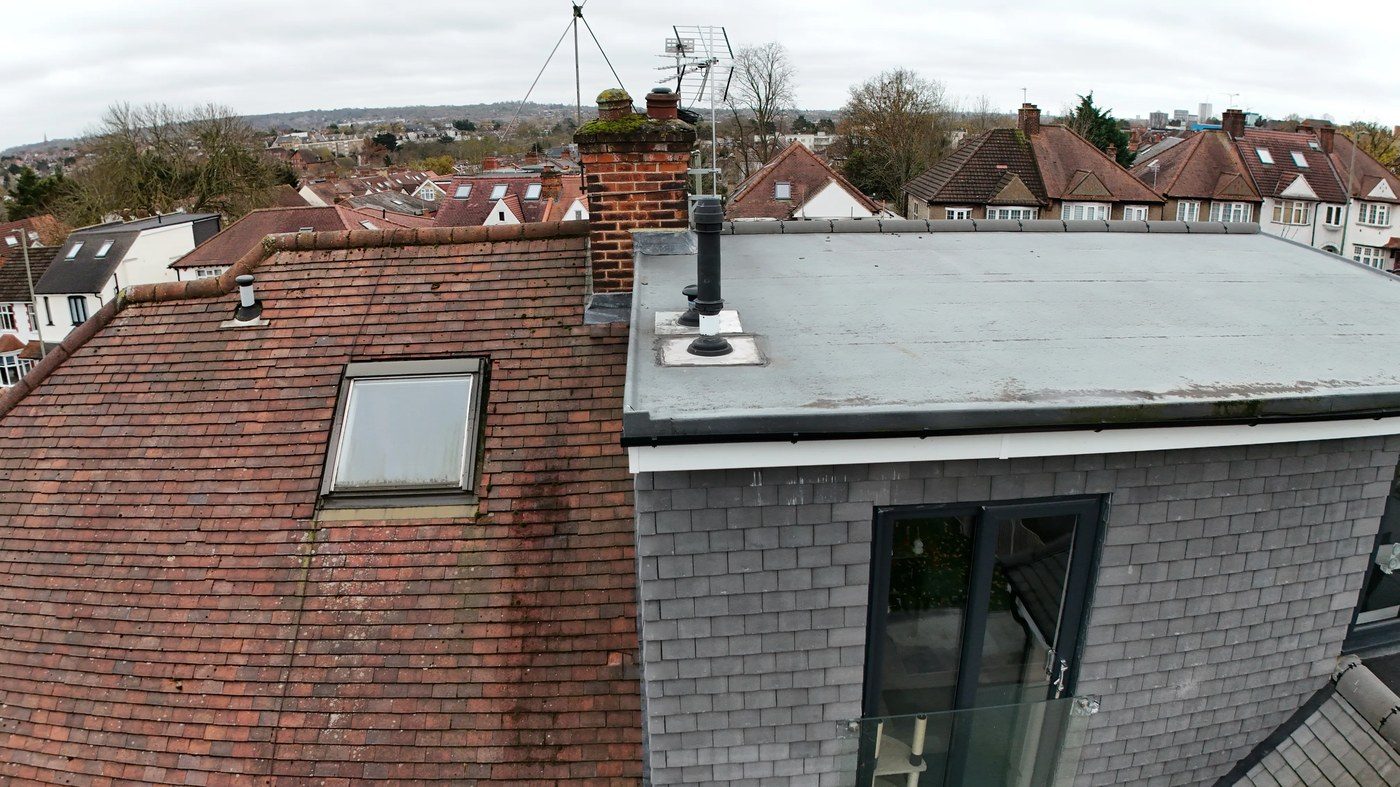 Oblique wide view of chimney stack with moss colonisation and neighbouring red tile roof