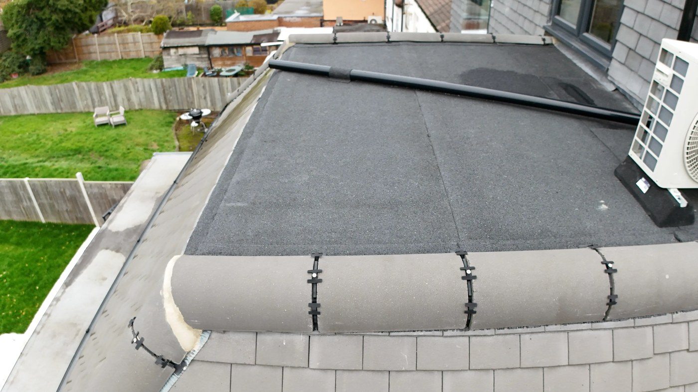 Close-proximity drone view of swept hip tile perimeter showing concrete bonnet hip tiles with pale foam filler