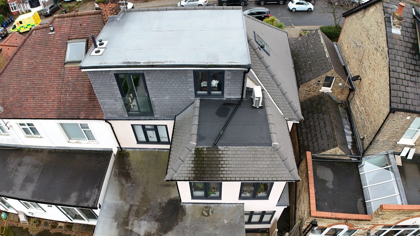 Aerial view showing property in wider context with adjacent flat roofs showing surface staining
