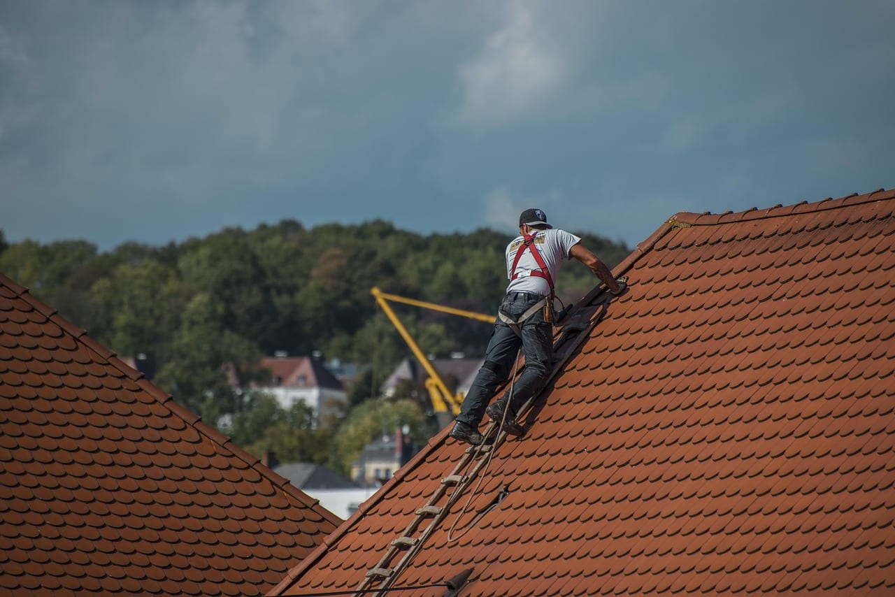 Roofer inspecting tiles on a pitched roof